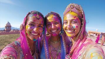 vibrante holi celebracion con Tres mujer en tradicional atuendo foto