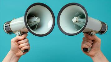 Two Hands Holding Megaphones Against a Blue Background photo