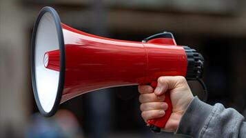 Hand Holding Red Megaphone Against Blurred Background photo