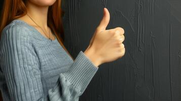 mujer dando un pulgares arriba en contra un oscuro texturizado pared foto