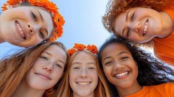 grupo de alegre joven amigos con naranja flores al aire libre foto