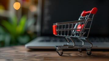 Miniature Shopping Cart on a Desk With Blurred Laptop Background photo