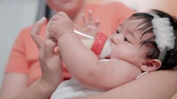 een moeder feeds haar baby melk van een klein fles in haar hand. video