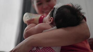 Close up Young mother breastfeeds her baby with breast milk from a bottle.child eats and looks at mother video