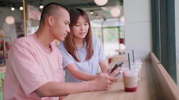 Couple looking at mobile phone while talking lovingly and expressing their love in a restaurant video