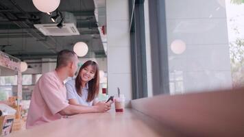 zwei Paare saß und sprach während ruhen beim ein Cafe. Sie sah beim ihr Smartphones. video