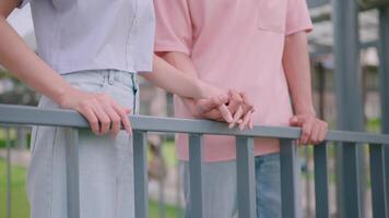 avvicinamento di un' allegro asiatico uomo e donna Tenere mani in piedi insieme su il balcone di un' costruzione. Sorridi e parlare felicemente video