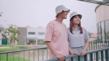 A young couple is having a happy date with their boyfriend enjoying spending time together, cuddling and relaxing. A man and a woman stand on a bridge and look at a green space. video