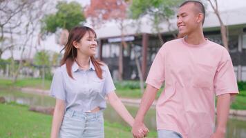 A man holding hands enjoying and relaxing walks forward into the sunlight. With an Asian woman in a natural field, starting a family dream video