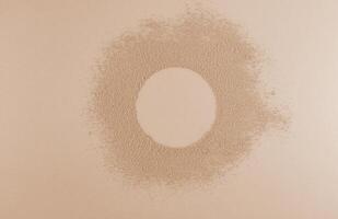 An empty round space on loose powder in a natural beige color. Advertising concept of the product. Top view. space for text. Beige background. photo