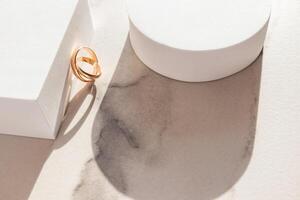 Two classic gold rings leaned on a white cube podium. Marble background. Sunlight. shadow of the figures. A copy of the space. Layout for design. photo