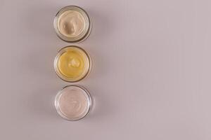 A jars with cosmetic cream of different textures and colors for face and body skin care. Beige background. space for text. Top view photo