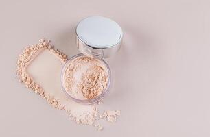 Open cosmetic jar with silver lid with delicate loose powder on pastel background with powder swatch. Top view. A copy space. photo