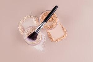 Two types of powder in cosmetic jars and delicate swatches on a beige background, a brush for contouring the face. Top view. makeup concept. photo