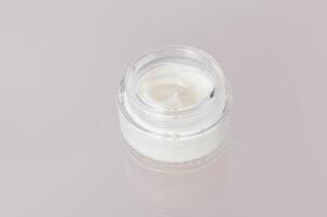 Delicate texture of white cosmetic cream for face and body skin care in jar on a glass background with reflection. layout. photo