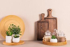 Set of glass jars with spices on a round wicker tray on a stone countertop. Potted houseplants. Kitchen background. Front view. photo