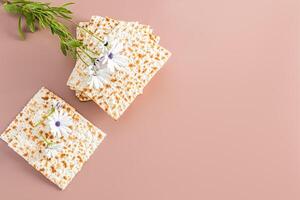 Concept of celebrating the Jewish holiday of Passover. A stack homemade matzoth on beige background and a delicate flower. Top view. a place for text. photo