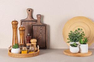 Set of wooden spice mills and glass jars with spices on a round wicker tray on a stone countertop in the interior of a modern kitchen space photo