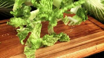 Pieces of Beijing cabbage fall on a wooden cutting board. Filmed is slow motion 1000 fps. High quality FullHD footage video