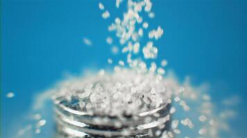 A showing salt being poured into a salt shaker and a jar on a blue background. Filmed on a high-speed camera at 1000 fps. . High quality FullHD footage video