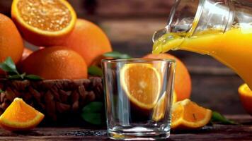 un lanzador de refrescante Valencia naranja jugo es siendo vertido dentro un vaso vasos en el mesa. el vibrante líquido es hecho desde delicioso naranjas, tal como rangpur, clementina, y naranja video