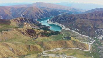 aereo. bellissimo un' montagna strada serpeggiante giù a partire dal un' passaggio per alpino lago video