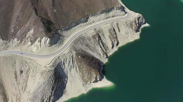 Aerial. mountain road stretches along the shore of an alpine lake video