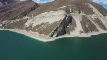 Aerial. alpine lake with turquoise water is surrounded by spring mountains video