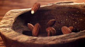 Almendras, un natural ingrediente, son cascada sobre un de madera mesa. esta de cerca, macro fotografía vitrinas el nueces en su caparazón, retratar un todavía vida de natural comidas video