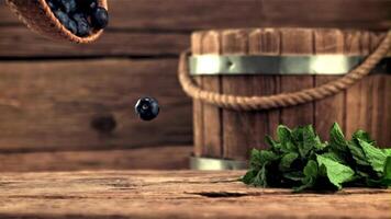 The super slow motion of the blueberries falls from the basket to the table. On a wooden background. Filmed on a high-speed camera at 1000 fps. video