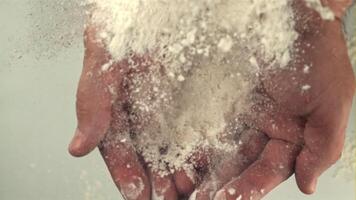 The super slow motion of the flour falls on the man's hands. On a white background.Filmed on a high-speed camera at 1000 fps. High quality FullHD footage video