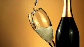 Stream of champagne pours into a glass of air bubbles. On a yellow background.Filmed is slow motion 1000 frames per second. High quality FullHD footage video