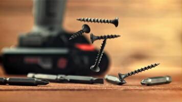 Self-tapping screws fall on a wooden table. On a wooden background. Filmed is slow motion 1000 frames per second. video