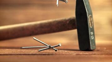 Nails fall on the table with a hammer. On a wooden background.Filmed is slow motion 1000 frames per second. High quality FullHD footage video