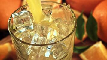 Orange juice is poured into a glass of ice. Macro background. Filmed is slow motion 1000 frames per second.High quality FullHD footage video