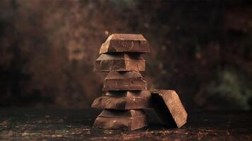 super langzaam beweging vallend stukken van bitter, donker chocola Aan een piramide van chocola plakjes. gefilmd Aan een hoge snelheid camera Bij 1000 fps. video