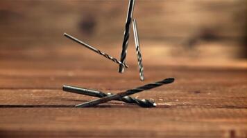 Drill bits fall on the wooden table. On a wooden background. Filmed is slow motion 1000 fps. video