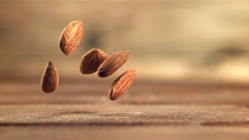 amandes tomber sur le tableau. sur une en bois Contexte. filmé est lent mouvement 1000 cadres par deuxième. haute qualité Full HD métrage video