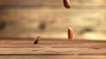 amandes tomber sur le tableau. sur une en bois Contexte. filmé est lent mouvement 1000 cadres par deuxième. haute qualité Full HD métrage video