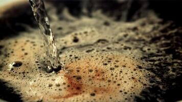 A jet of hot water pours into black coffee with air bubbles. Macro background. Filmed is slow motion 1000 frames per second. video