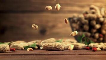 Peeled peanuts fall on the table. On a wooden background.Filmed is slow motion 1000 fps. High quality FullHD footage video