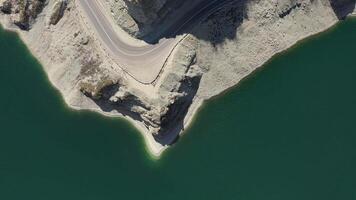 Aerial top down. mountain road winds along a high cliff on the shore of a lake video