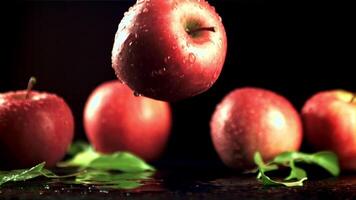 een vers rood appel valt Aan een tafel met spatten van water. Aan een zwart achtergrond. gefilmd is langzaam beweging 1000 fps. video