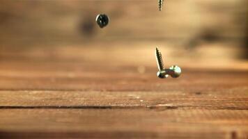 autotaraudeur des vis tomber sur le tableau. sur une en bois Contexte. filmé est lent mouvement 1000 cadres par deuxième. video