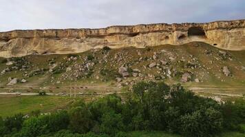 un' mandria di cavalli si sposta lungo un' bianca roccioso montagna a tramonto. fuco Visualizza video