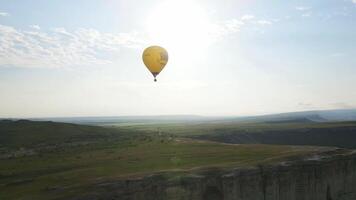 A yellow balloon flies in the sky over the White Rock in the Crimea. Drone view video