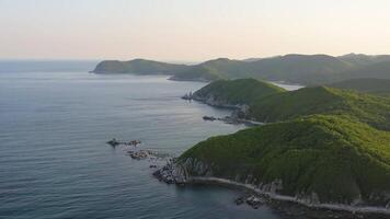Cinematic shot of endless mountains and forests on the sea coast at sunset video