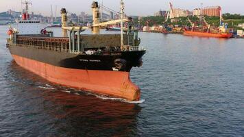 Cargo rusty ship sails on the sea at sunset. Drone view video