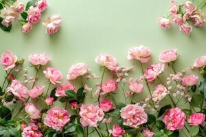 Border made of pink roses and peonies isolated on pastel green background photo