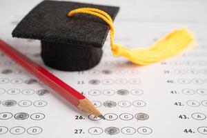 Graduation gap hat and pencil on answer sheet background, Education study testing learning teach concept. photo